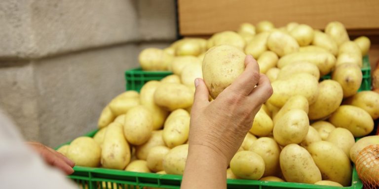 cropped-portrait-senior-caucasian-woman-stretching-hand-with-big-potato-it-ready-put-it-her-basket-while-shopping-supermarket-looking-vegetables-cooking-family-dinner-1050x525